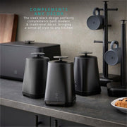 The Hale Retail Company Swan Stealth black iron bread bin and tea, coffee, and sugar canister set on a kitchen counter.